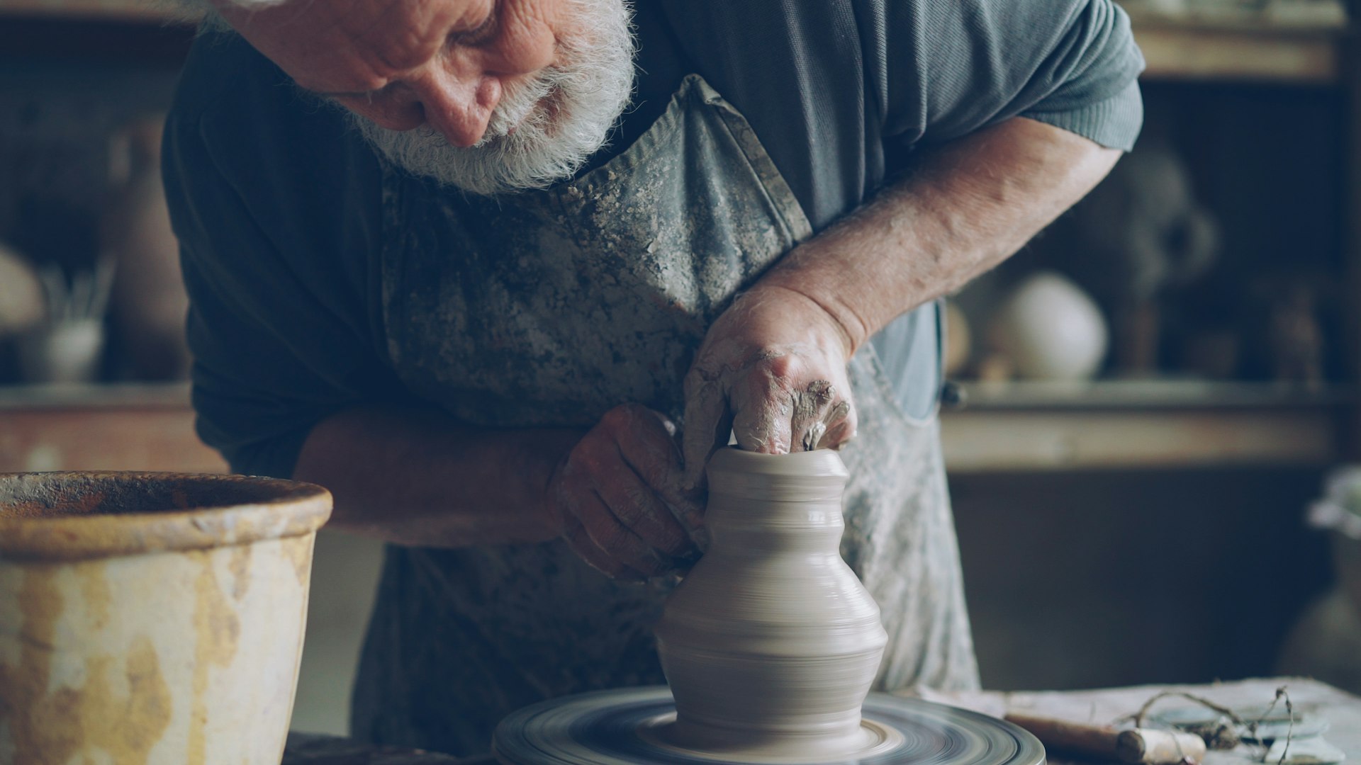 A potter shapes clay on a spinning wheel.